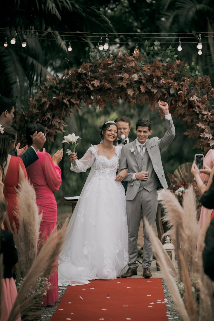 Mastering the First Impression: Your intriguing post title goes here Happy couple celebrates their wedding under a floral arch with loved ones cheering on a festive day.